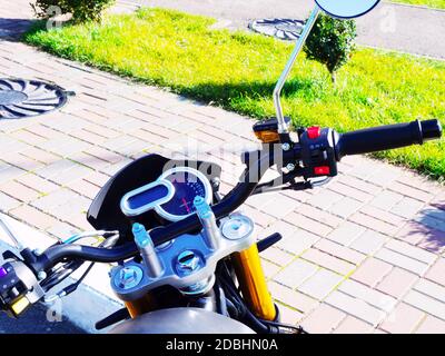 Il volante di una motocicletta si trova sul marciapiede in una giornata di sole Foto Stock