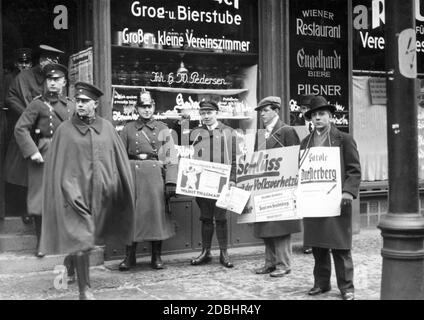 'Schutzpolizisten voto alle elezioni presidenziali. I sostenitori dei partiti KPD, DNVP/Stahlhelm e Hindenburg si trovano di fronte alla stazione di scrutinio e la campagna con i manifesti. Il KPD si batte con ''per il lavoro socialismo di pace'', i sostenitori di Hindenburg con 'Stop the incitement of the people vote Paul von Hindenburg'' e il DNVP/Stahlhelm con 'logan Duesterberg'. Foto Stock