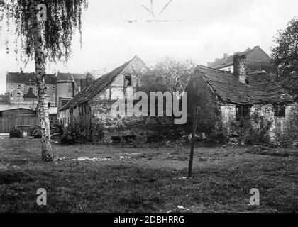 La fotografia del 1932 mostra la vista posteriore di un fienile dilapidato e di una stalla abbandonata di un'antica fattoria a Berlino a Muellerstrasse 16, dietro la quale le case e gli affittuari più moderni della città in crescita già torre. Foto Stock