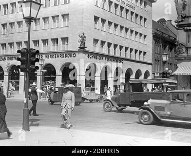 'Di fronte alla Haus der Schweiz con il Tellknaben all'angolo, dove si trova il 'Schweizer Verkehrsbuero', un agente di polizia stradale regola il traffico e il trambusto all'intersezione di Unter den Linden e Friedrichstrasse. L'agenzia di viaggi offre destinazioni come Egitto, Palestina, il Levante, India o Asia orientale. La foto è stata scattata nel 1937." Foto Stock