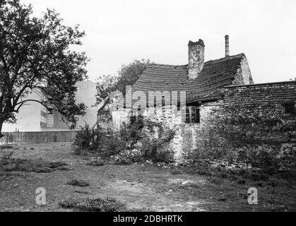 La fotografia del 1932 mostra una stalla dilapidata e abbandonata di una vecchia fattoria a Berlino a Muellerstrasse 16, dietro la quale sono già in piedi una casa più moderna e un camino della città in costante crescita. Foto Stock