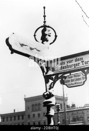 'La fotografia degli anni '30 mostra un cartello stradale innevato alla porta di Brandeburgo a Berlino. Dice: '' Piazza di fronte alla porta di Brandeburgo'' con un cartello sotto: ''rivelatore di incendio a Unter den Linden 76 / angolo di Neue Wilhelmstr.''' Foto Stock