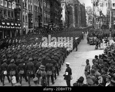 Adolf Hitler (in piedi in una Mercedes sulla destra) prende il saluto degli aviatori dello Stahlhelm sulla cosiddetta Adolf-Hitler-Platz. Di fronte ad essa un team di telecamere filma l'evento. Sullo sfondo a sinistra, una parte della Chiesa del Sebaldo, a destra lo Schoener Brunnen. Sull'estrema sinistra si trova una fascia di ottone. Foto Stock