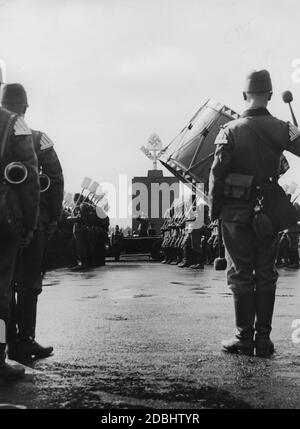 Adolf Hitler in una Mercedes sul campo di Zeppelin, prende il saluto dei circa 50,000 uomini del Reich Labour Service. In primo piano è una band musicale con batteria e strumenti a vento. Dietro Hitler, il Memoriale del lavoro, in cui ha avuto luogo la commemorazione dei morti. Foto Stock