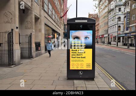 La gente passa accanto a un cartello NHS Coronavirus Test su Charing Cross Road, Londra durante il secondo blocco nazionale in Inghilterra. Foto Stock