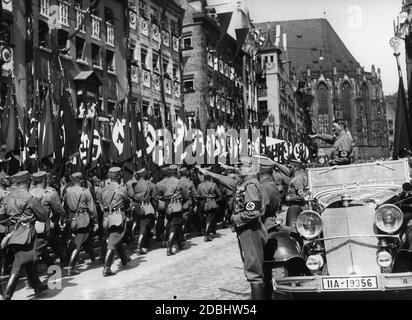 Adolf Hitler, in piedi nella sua Mercedes, prende il saluto dei portatori di bandiera SA mentre marciano oltre sulla piazza principale del mercato di Norimberga, la cosiddetta Adolf-Hitler-Platz. Davanti a lui sulla sinistra c'è Franz Pfeffer von Salomon, sulla destra Viktor Lutze. Sullo sfondo, una parte della Chiesa del Sebaldo. Foto Stock