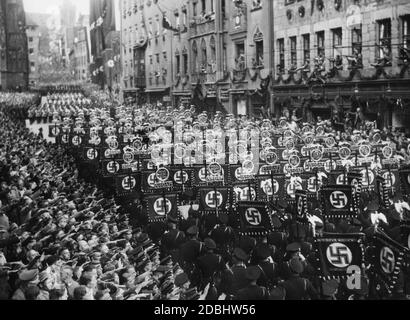 Sulla strada per il cosiddetto Adolf-Hitler-Platz le formazioni dei portatori di standard delle SS attraversano le strade di Norimberga, accolte dal popolo di Norimberga. Foto Stock