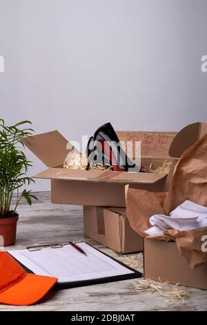 Cartoni con scarpe, documenti di consegna e tappo arancione. Foto Stock