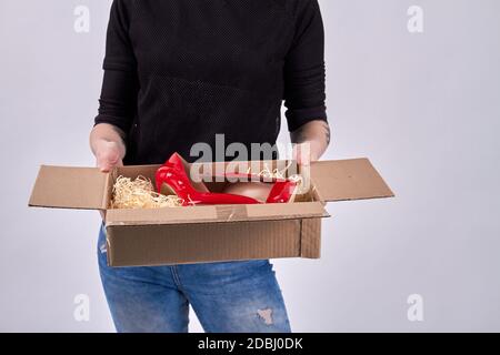 Ritratto di ragazza che sboxe un pacco con scarpe rosse. Foto Stock