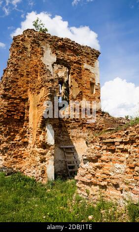 dilapidato con poole vecchia torre in mattoni della fortezza dell'edificio, in mattoni rossi, parte del muro è soggetto a distruzione e danni Foto Stock