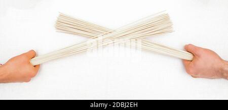 Scopa da massaggio di bambù nelle mani di due massaggiatori isolati sfondo bianco Foto Stock