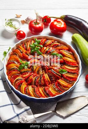 ratatouille, stufato di melanzane a fette, zucchine, cipolla e patate con salsa di pomodoro, ingredienti sullo sfondo, cucina francese, verticale Foto Stock