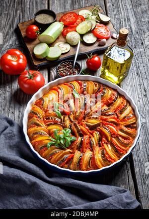 ratatouille, stufato di melanzane a fette, zucchine, cipolla e patate con salsa di pomodoro, ingredienti sullo sfondo, cucina francese, verticale Foto Stock