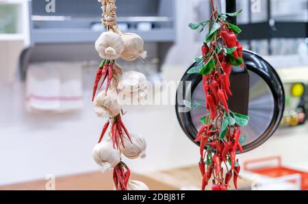Mazzi di aglio decorativo e peperoncini rossi all'interno della cucina. Foto Stock