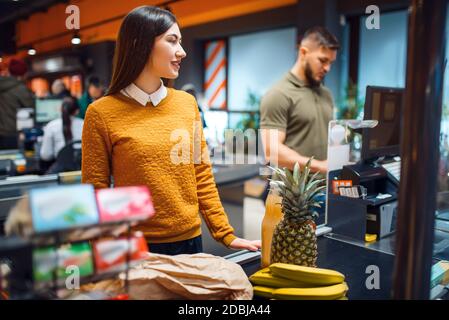 Coppia di famiglie al check-out nel negozio di alimentari. Uomo e donna con carrello che acquista bevande e prodotti sul mercato, clienti che pagano cibo e bevande Foto Stock