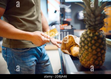 Uomo al check-out nel negozio di alimentari. Uomo con carta di credito sul mercato, cliente che paga cibo e bevande nel supermercato Foto Stock