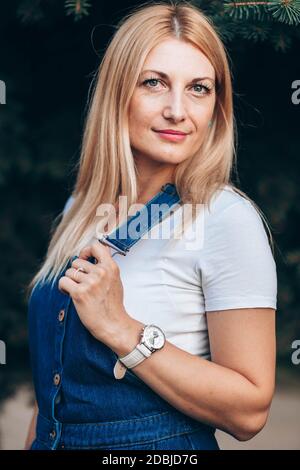 Primo piano ritratto di donna bionda dagli occhi blu in jeans con sospetti Foto Stock