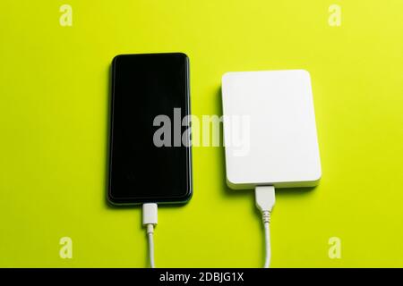 Smartphone che si connette al disco rigido esterno su sfondo verde.tecnologia , concetto di archiviazione dati mobile. Foto Stock