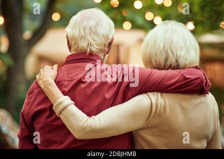 In vita di coppia anziana abbracciando e guardando il loro camper mentre si gode la serata. Concetto di viaggio e stile di vita Foto Stock