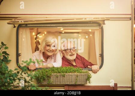 Felice coppia anziana che riposa nel loro camper guardando fuori dalla finestra. Concetto di viaggio e stile di vita Foto Stock