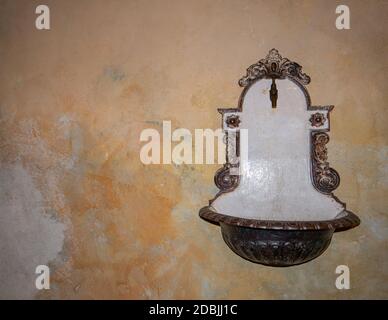 Un vecchio lavandino antico è appeso su un muro rustico Foto Stock