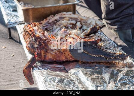 Closeup di coccodrillo di acqua salata giovanile alla griglia in tutto il dettaglio con carne esposta e testa con mascella e denti visibili. Foto Stock