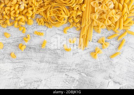 Concetto di cucina italiana e design del menu. Vari tipi di pasta Farfalle, Pasta A riso, Orecchiette Pugliesi, Gnocco Sardo e Farfalle su fondo di pietra bianca con piatto Lay.Copy Cpase Foto Stock