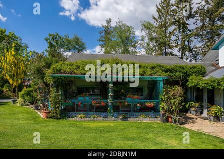 pergola in splendido giardino estivo, verde conifere, verde erba e sole pomeridiano. Concetto di giardinaggio di lusso con fiori Foto Stock