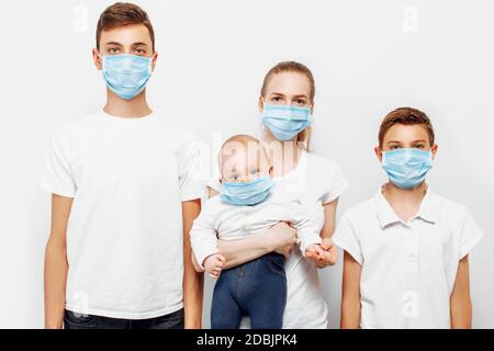 I genitori e i bambini della famiglia indossano maschere mediche per prevenire le infezioni, le malattie respiratorie trasportate dall'aria, il coronavirus isolato su uno sfondo bianco Foto Stock