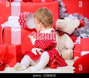 Doni per i bambini prima di natale. Attività di Natale per i bambini piccoli. Regali di natale per bambino. Cose da fare con i bambini a Natale. Little Baby girl giocare vicino a pila di confezioni regalo. Vacanza in famiglia. Foto Stock