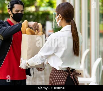 Deliverly asian bike man raccogliere borsa di prodotti da forno dal negozio di prodotti da forno per consegnare al cliente che effettua l'ordine online. Concetto di servizio di cibo in n Foto Stock