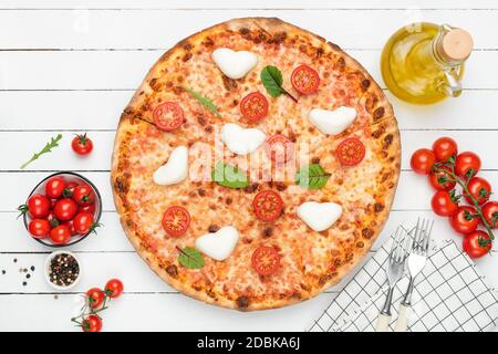 Pizza Margarita o margherita con mozzarella a forma di cuore su fondo bianco in legno, vista dall'alto Foto Stock