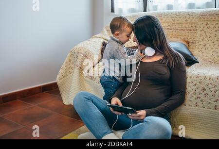 Il bambino rivendica l'attenzione della sua madre incinta Foto Stock