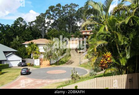 CUL-de-sac nel sobborgo di Queensland Australia con case su colline con vialetti ripidi e alberi di gomma alti dietro e tropicale architettura paesaggistica Foto Stock