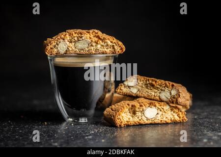 Biscotti dolci alla cantuccina. Biscotti alle mandorle e tazza di caffè su tavola nera. Foto Stock