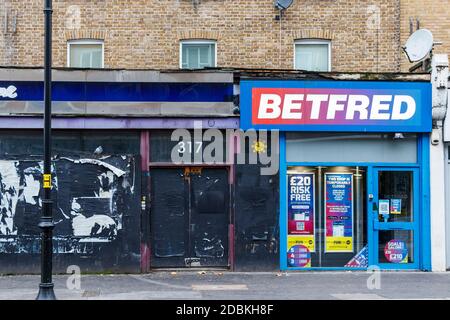 Il negozio di scommesse betfred, chiuso durante il secondo blocco pandemico del coronavirus, accanto a un negozio vuoto e imbarcato a Kentish Town, Londra, Regno Unito Foto Stock