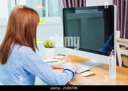 Donna d'affari asiatica indossare maschera facciale protettiva lavorare da casa ufficio con computer desktop sotto quarantine malattia coronavirus fare videochiamata c Foto Stock