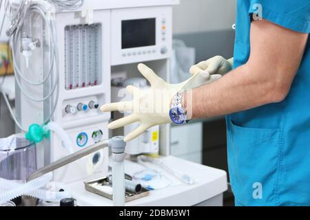 Il medico mette i guanti sullo sfondo di un ventilatore. Foto irriconoscibile. Spazio di copia. Foto Stock