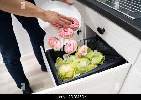 Uomo gettando via cibo rimane in Bin Foto Stock