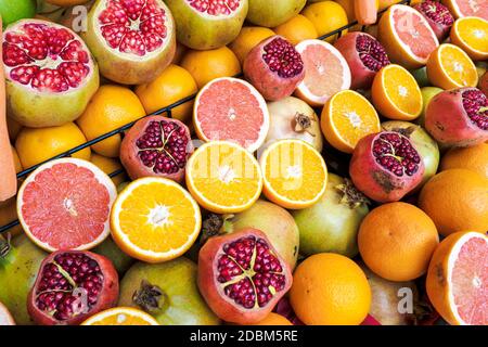 Melograni aperti, arance tagliate, pompelmo al banco del mercato in Turchia per preparare un succo sano. Frutta fresca sfondo, vista dall'alto Foto Stock