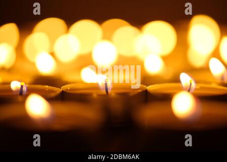 Candele che bruciano. Profondità di campo poco profonda. Molte candele di natale che bruciano di notte. Sfondo astratto candele. Molte fiamme di candela che si illuminano sulla parte posteriore scura Foto Stock