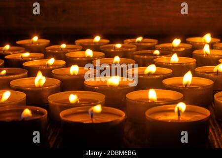 Candele che bruciano. Profondità di campo poco profonda. Molte candele di natale che bruciano di notte. Sfondo astratto candele. Molte fiamme di candela che si illuminano sulla parte posteriore scura Foto Stock