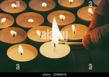 Candele che bruciano. Profondità di campo poco profonda. Molte candele di natale che bruciano di notte. Sfondo astratto candele. Molte fiamme di candela che si illuminano sulla parte posteriore scura Foto Stock