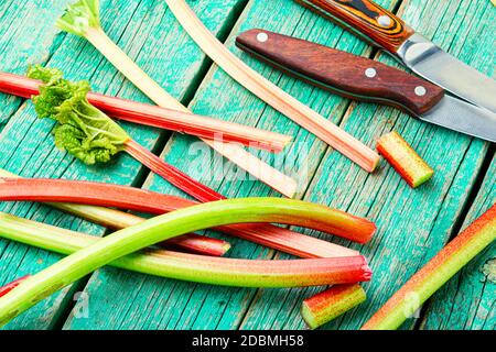 Rhubarb fresco stelo su retro tavola di legno. Pacchetto di steli e pezzi rabarbaro Foto Stock