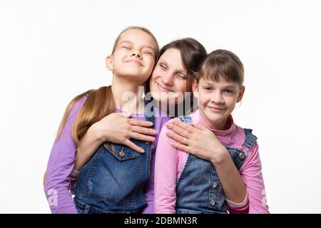 Mamma si aggrappò felicemente alle sue figlie, isolate su sfondo bianco Foto Stock