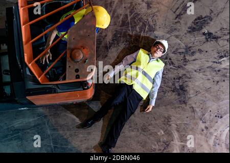 Responsabile magazzino asiatico sdraiato sul pavimento del magazzino dopo un incidente dal carrello elevatore. Utilizzo per il concetto di assicurazione sicurezza e aziendale. Antenna superiore Foto Stock