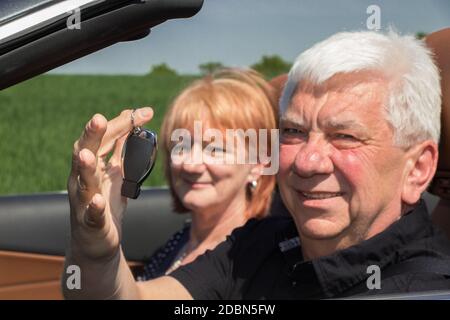 Uomo anziano con le chiavi dell'automobile e della sua donna in un automobile di sport Foto Stock