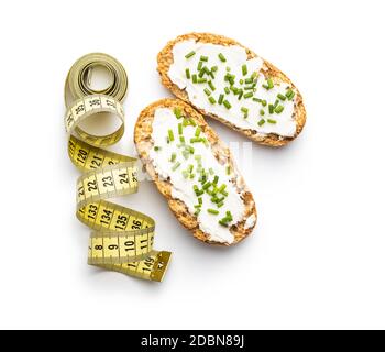 Cracker e nastro di misurazione. Pane croccante con formaggio cremoso e erba cipollina. Isolato su fondo bianco. Foto Stock