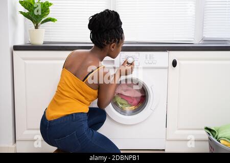 Persona mano impostazione lavatrice per vestiti lavanderia Foto Stock