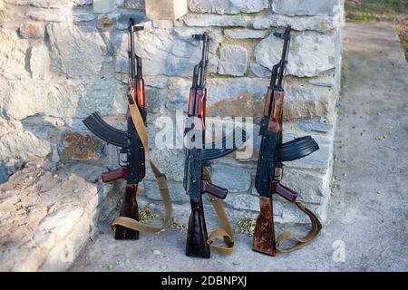 Tre Kalashnikov AKM vicino a un muro di pietra Foto Stock